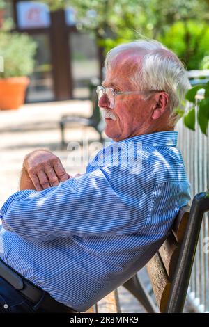 Older grey haired retired man sitting on garden bench in city center - Tours, Indre-et-Loire (37), France. Stock Photo