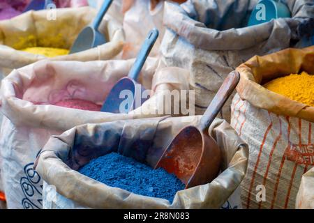 Pigment dust sacks in a market in Marrakesh, with intense blue, yellow, pink, violet,orange, red colors, on a intense blue wall Stock Photo