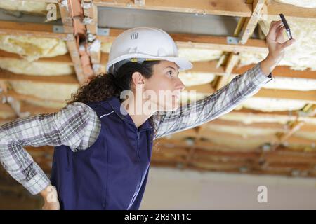 female builder taking a picture of the roof Stock Photo