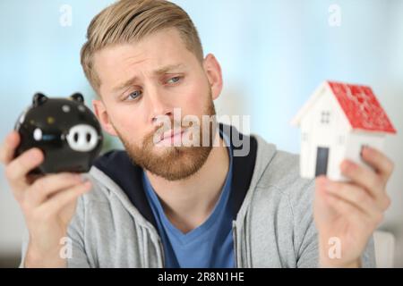 confused man holding piggy bank with serious face Stock Photo