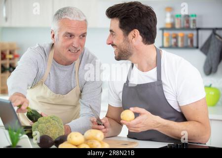 senior father and son cooking soup indoors Stock Photo