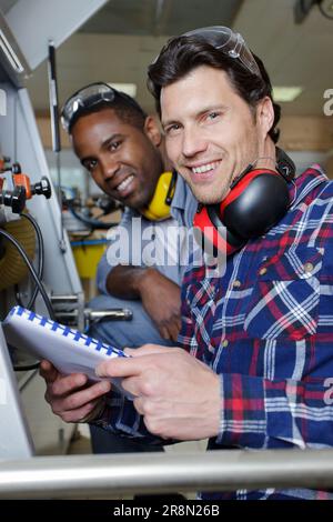 two engineers using a machine in a factory Stock Photo