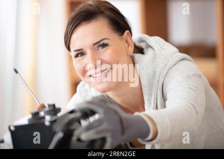 happy female builder with screwdriver fixing socket indoors Stock Photo
