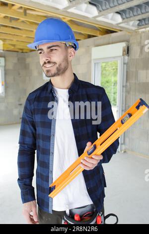 young handsome builder holding a spirit level Stock Photo