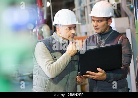 workers with hardhat on looking at the laptop screen Stock Photo