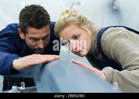 male and female mechanics inspecting surface of panel Stock Photo