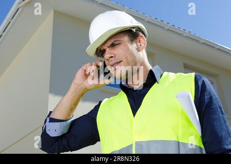 engineer wearing safety helmet and talking smartphone outdoors Stock Photo