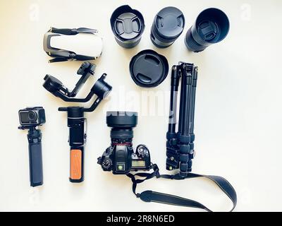 Flat lay composition with equipment for professional photographer on white table background. Gimbal, lens, drone, tripod, camera, action camera outdat Stock Photo