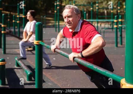 Elderly man is doing push-ups from the crossbar Stock Photo