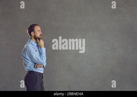 Side view of thinking businessman standing isolated on grey copy space background Stock Photo