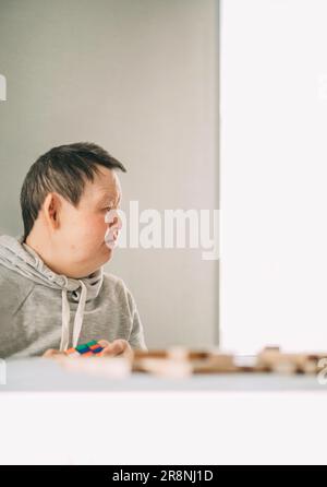 elderly Down syndrome woman at home play in tower from wooden blocks Stock Photo
