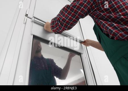 Worker installing roller window blind indoors, closeup Stock Photo