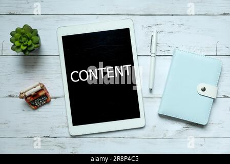 Online digital content business technology concept. Top view of plant,pen,notebook and tablet written with Content on white wooden background. Stock Photo