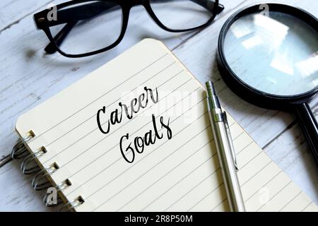 Magnifying glass,pen,sunglasses and notebook written with 'CAREER GOALS' on white wooden background. Stock Photo