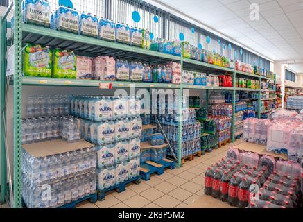 Italy - June 22, 2023: Plastic bottles of water and soft drinks on pallets and shelves for sale in Italian discount store supermarket Stock Photo