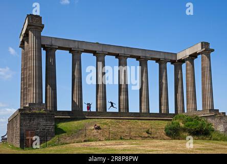 National Monument, Calton Hill, Edinburgh, Scotland, UK. 22nd June 2023. One tourist caught in the act of leaping in the air as his partner takes a photograph of the moment. The majority of tourists who visit Calton Hill climb up to be photographed on the historic building. The National Monument of Scotland, is Scotland's national memorial to the Scottish soldiers and sailors who died fighting in the Napoleonic Wars. It was intended, according to the inscription, to be 'A Memorial of the Past and Incentive to the Future Heroism of the Men of Scotland' Credit: Arch White/alamy live news. Stock Photo