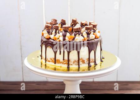 Twix inspired cake with melted chocolate, cookies, salted caramel and sweet bar Stock Photo