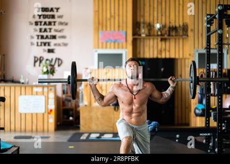 Photo with copy space of a strong man doing squats with weight using a bar in a gym Stock Photo