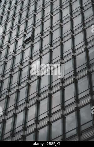 An intriguing abstract composition captures a glass facade with one window open, inviting curiosity and creating a sense of mystery and possibility. Stock Photo