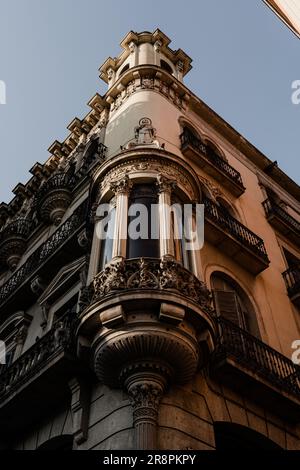 The golden hour casts a warm glow on a corner of a building in Barcelona, illuminating its architectural details and creating a captivating play of li Stock Photo