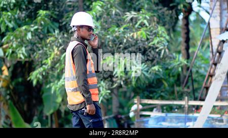 Construction concept: engineer use smartphones in the Construction concept: engineer use smartphones in the workplace. Handsome engineers wearing helm Stock Photo