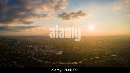 Aerial view from high altitude of distant city covered with puffy cumulus clouds forming before rainstorm in evening. Airplane point of view of cloudy Stock Photo
