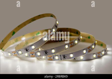 LED tape glowing white and rolled up in rings. Suitable for decorative indoor hidden illumination, holiday Christmas lights, party decorations Stock Photo
