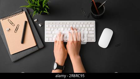 Hands of woman using computer keyboard at dark workplace, top view Stock Photo