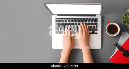 Hands of woman using laptop on grey background with space for text, top view Stock Photo