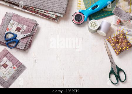 Patchwork log cabin blocks, stack of blocks, sewing accessories on white wooden surface Stock Photo