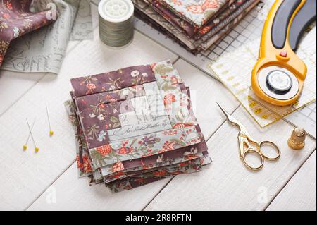 Patchwork log cabin blocks, stack of blocks, sewing accessories on white wooden surface Stock Photo