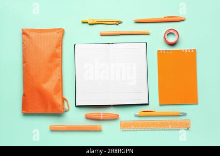 Notebooks with pencil case and different stationery on turquoise background Stock Photo