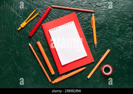 Notebooks with different school stationery on grunge green background Stock Photo
