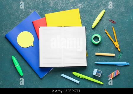 Notebooks with different school stationery on grunge turquoise background Stock Photo