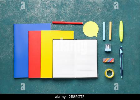 Notebooks with different school stationery on grunge turquoise background Stock Photo