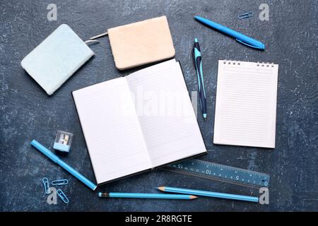 Notebooks with different stationery on grunge dark blue background Stock Photo