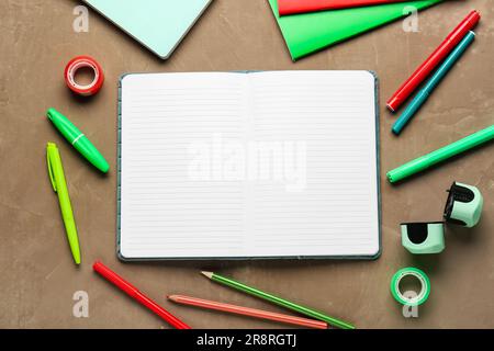 Notebooks with different school stationery on grunge brown background Stock Photo