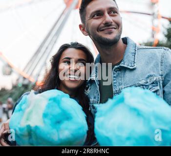 Young happy couple standing together holding blue cotton candy Stock Photo