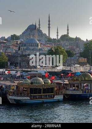 Balik Ekmek (fish sandwich) boats at Eminonu beside the Golden Horn river in Istanbul, Turkey. Suleymaniye Mosque on the hill behind Stock Photo