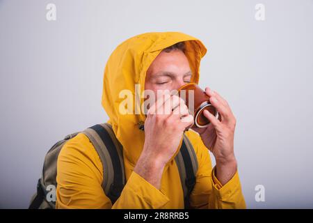 A man drinks healthy herbal tea while wearing a raincoat Stock Photo