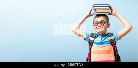 Funny school boy in glasses holding books on his head Stock Photo
