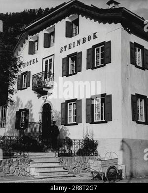 Pontresina -- Life in the High Alps of Switzerland. Formerly A Coach Station, the Hotel Steinbok is one of the two oldest hotels at Pontresina. It is built in traditional Swiss style. The postman who takes mail round in a hand-cart, is seen leaving. January 22, 1948. (Photo by Pictorial Press Photo). Stock Photo