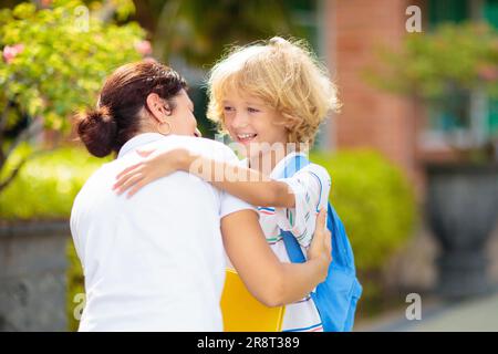 Mother bringing child to school. Parents pick up little boy after class. Young mom picking up kid after lessons in kindergarten or preschool. Stock Photo