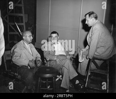 Huddle Of 'The Brains'... On the set of Metro-Goldwyn-Mayer's 'The Beginning or the End', gripping story of the atom bomb, a discussion of complex phases of the picture takes place between Director Norman Taurog, Studio Executive James K. McGuinness and Dr. Henry T. Wensel, one of the film's eight technical advisors. Robert Walker and Brian Donlevy head the picture 'W Wtellar cast, which includes Tom Deake, Beverly Tyler, Audrey Totter, Home Cronyn, Hurd Hatfield and Joseph Calleia. Samuel Marx produced. June 4, 1953. Stock Photo