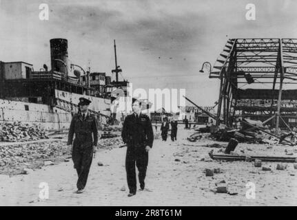 Allied War Chiefs Meet In Tunis -- Air Chief Marshal Sir Arthur Tedder (right) walking through the wrecked harbour at Tunis during his visit to the town so on after it was occupied by the Allies. With him is S/LDR. Lancaster, personal staff officer to Air Marshal Sir Arthur Coningham. Air Chief Marshal Sir Arthur Tedder, Commander in-Chief, Mediterranean Air command met Allied war chiefs during his visit to Tunis and the Tunisian front line airfields. July 12, 1943. (Photo by British Official Photo). Stock Photo