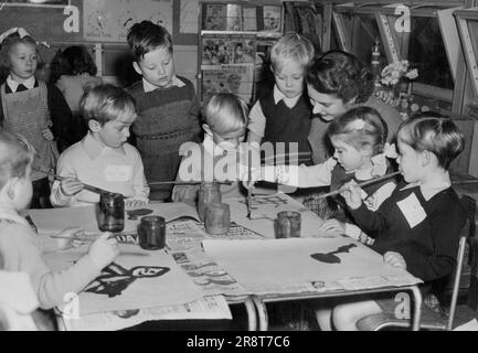 First Lesson For The Quads: Seen with other pupils at Cuckoo Hal Lane School, are the Taylor quads engrossed in their first lesson, painting, watched by their teacher Miss Pamela Perrin of Tottenham. The quads seated round the table are (left to right) Robert, Paul, Annette and Kevin (suitably 'labelled' for identification purposes). Those famous four children, the Taylor quads, set out form their Mottingham Road, (Edmonton) home this morning with mixed feelings. For today, Annette, Robert, Kevin and Paul, who were years old last week, reached another milestone in their young lives and be… Stock Photo