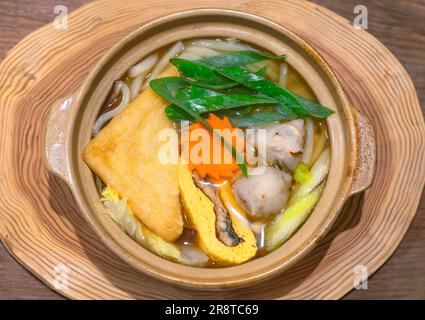 Japanese udon noodles made from wheat flour served as stewed yaki udon with a deep-fried tofu pouch aburaage, long onion naganegi, cabbage, eel in ome Stock Photo