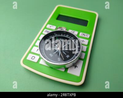 Closeup green calculator with compass on a green background. Business concept. Stock Photo