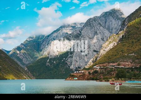 mountains tower over small villages on the shores of Lake Koman, a reservoir constructed on the Drin River in northern Albania Stock Photo