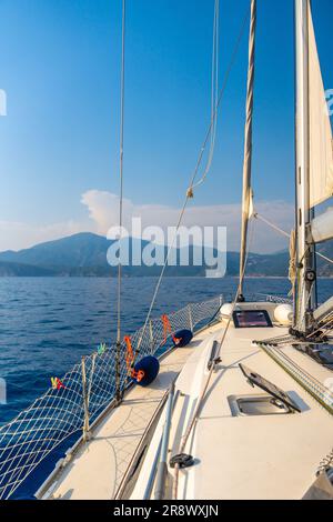 Yacht sailing in an open sea. Close-up view of the deck, mast and sails. Clear sky, waves and water splashes Stock Photo